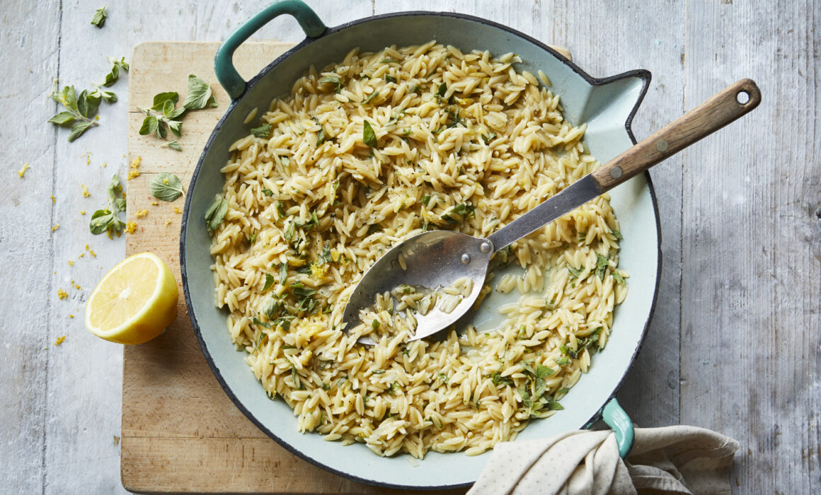 Orzo Risotto with Lemon in a large cast iron pan with a spoon in